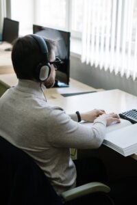 Un homme malvoyant lit un livre en braille à l'intérieur avec des écouteurs.