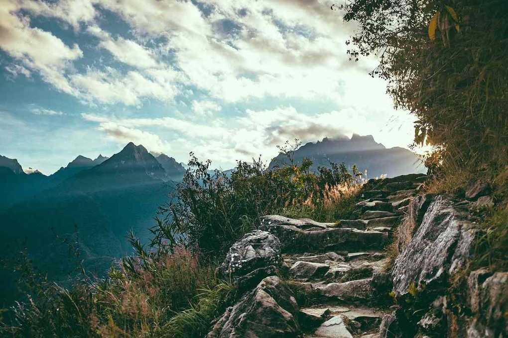 Sentier de montagne avec rochers et végétation sous un ciel nuageux Sentier de montagne avec rochers et végétation sous un ciel nuageux